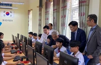 Các đại biểu hướng dẫn các em học sinh sử dụng máy tính mới.