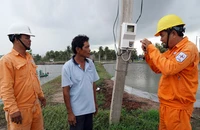Công nhân Điện lực huyện Mỹ Xuyên, tỉnh Sóc Trăng hướng dẫn, tuyên truyền cho các hộ gia đình sử dụng điện an toàn trong nuôi tôm. (Ảnh: THẾ VĨNH)