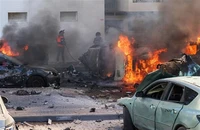 Người dân dập các đám cháy trên xe ô-tô sau vụ tấn công bằng rocket từ Dải Gaza tại Ashkelon (Israel), ngày 7/10/2023. (Ảnh: AFP/TTXVN)