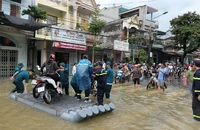 Lực lượng dân quân phường Minh Khai, thành phố Hà Giang đưa người dân qua đoạn đường ngập úng.