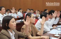 Các đại biểu Hội đồng nhân dân tỉnh Sơn La biểu quyết thông qua nghị quyết kỳ họp.