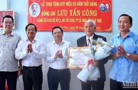 Phó Bí thư Tỉnh ủy Cà Mau Nguyễn Đức Hiển (giữa) trao Huy hiệu 65 năm tuổi Đảng và tặng hoa chúc mừng đảng viên Lưu Tấn Công.
