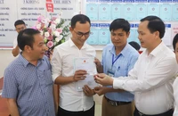 Phó Tổng Giám đốc Chu Mạnh Sinh trao thẻ bảo hiểm y tế của bé gái Đinh Bảo N. cho anh Đinh Tiến Hoàng.