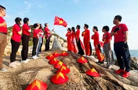 Du khách chào cờ đón ánh bình minh ở Mũi Đôi. Ảnh: THANH AN