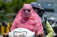 Người dân trùm kín tránh nắng nóng khi di chuyển tại Raipur, Ấn Độ. (Ảnh: AFP/TTXVN)
