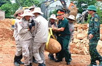 Các lực lượng phối hợp di dời, xử lý quả bom còn sót lại sau chiến tranh. (Ảnh: LA)