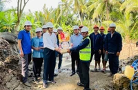 Thành viên Hội đồng thành viên EVNSPC Lê Xuân Hải (áo trắng) tặng quà động viên lực lượng lao động thi công dự án trên địa bàn tỉnh Bến Tre ngày 26 Tết.