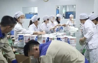 Công nhân đóng hộp thành phẩm tại cơ sở sản xuất sữa bột giả quy mô lớn vừa bị Công an thành phố Hà Nội triệt phá. (Ảnh: Báo Công an nhân dân)