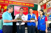 Đồng chí Nguyễn Phước Lộc, Phó Bí thư Thành ủy, Chủ tịch Ủy ban Mặt trận Tổ quốc Việt Nam Thành phố Hồ Chí Minh (bên trái) trao bánh giò mới nấu đến cán bộ, chiến sĩ trên nhà giàn DK1/10.