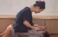 Người phụ nữ ngồi lên bụng cháu bé mặc cho bé khóc thét, sợ hãi (Ảnh cắt từ clip)