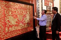 Ông Nguyễn Thế Hồng giới thiệu với du khách Tranh thêu chỉ vàng thời Nguyễn trưng bày trong Bảo tàng Hoàng gia Nam Hồng.