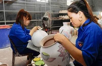 Vẽ hoa văn lên sản phẩm tại làng gốm Bát Tràng, Hà Nội. (Ảnh TUỆ NGHI)