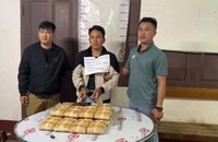 Đối tượng Tao Mùa (ở giữa) cùng tang vật 20 bánh (chứa 120 nghìn viên ma túy tổng hợp) khi bị lực lượng chức năng bắt giữ. (Ảnh: Công an Điện Biên)