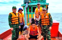 Nạn nhân Minh (ngồi) bị trôi dạt trên biển được Bộ đội Biên phòng Cà Mau cứu vớt đưa vào bờ an toàn.