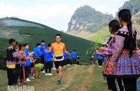 Học sinh dân tộc H'Mông đứng hai bên đường cổ động và tặng hoa cho các vận động viên.