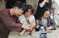 Nghệ nhân Ưu tú Huỳnh Sướng hướng dẫn các bạn sinh viên Hồng Công (Trung Quốc) trải nghiệm nghề mộc.