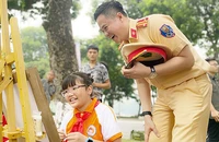 Cán bộ cảnh sát giao thông hào hứng với tác phẩm của thí sinh tại cuộc thi vẽ tranh "Thiếu nhi Thủ đô với an toàn giao thông" trong khuôn khổ Ngày hội.