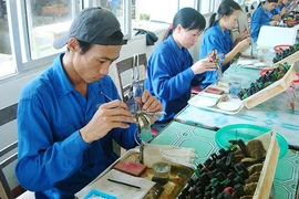 Công nhân thực hiện việc cấy ngọc trai tại Vân Đồn (Quảng Ninh). Ảnh: NGUYỄN HOA