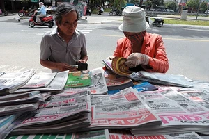 Độc giả mua báo tại một sạp báo trên đường Hàm Nghi, TP Đà Nẵng. Ảnh: NGỌC HÀ