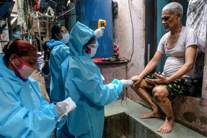 Nhân viên y tế đo thân nhiệt của người dân sống trong khu ổ chuột Dharavi, tại Mumbai. (Ảnh: Getty Images)