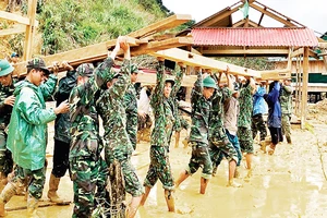 Cán bộ, chiến sĩ Đồn Biên phòng Ga Ry (Bộ Chỉ huy Bộ đội Biên phòng tỉnh Quảng Nam) giúp nhân dân huyện Tây Giang dựng lại nhà sau bão. Ảnh: PHAN TIẾN DŨNG