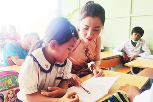 Cô giáo Dương Kim Huệ giúp bé làm quen với chữ Việt.