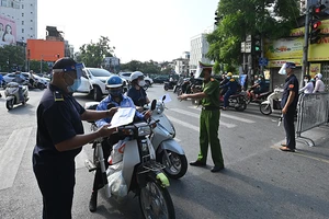 Lực lượng chức năng kiểm tra giấy tờ của người dân khi tham gia giao thông tại chốt phòng, chống dịch trên phố Đê La Thành (quận Ba Đình, Hà Nội). Ảnh: MINH HÀ