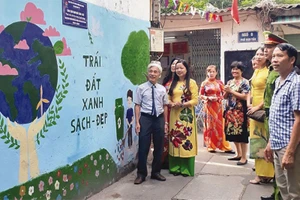 Ông Nguyễn Hữu Bằng (bên trái) cùng người dân Khu dân cư số 3 bên công trình tranh bích họa, làm đẹp diện mạo khu phố.