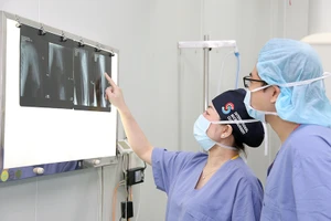 Các bác sĩ Bệnh viện Hữu nghị Việt Đức đánh giá hiệu quả điều trị cho người bệnh qua kết quả chụp X-quang. (Ảnh NGUYỄN ĐỨC)
