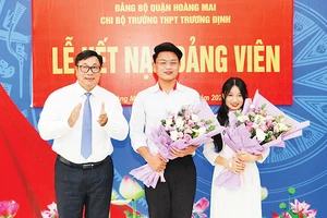 Đồng chí Nguyễn Quang Hiếu, Bí thư Quận ủy, Chủ tịch HĐND quận Hoàng Mai tặng hoa chúc mừng hai học sinh Trường THPT Trương Định được kết nạp vào đảng.