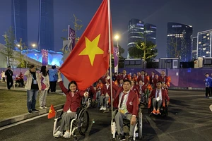 Kình ngư Võ Thanh Tùng (bên phải) vinh dự cầm cờ Việt Nam tại lễ khai mạc Asian Para Games 4.
