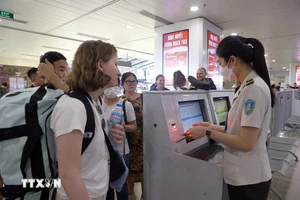 Nhân viên an ninh hàng không kiểm tra giấy tờ hành khách trước khi vào khu vực soi chiếu. (Ảnh: TTXVN)