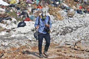 Phóng viên ảnh tác nghiệp trong môi trường độc hại tại bãi rác Nam Sơn, huyện Sóc Sơn, TP Hà Nội. Ảnh: Phạm Ngọc 