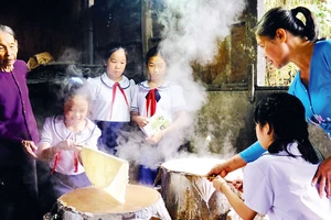 Nghệ nhân Đặng Thị Túy Phong (ngoài cùng bên trái) và con gái hướng dẫn học sinh trải nghiệm tráng bánh.