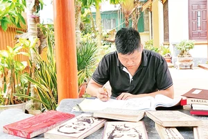 Nghệ nhân trẻ Nguyễn Công Đạt say mê với công việc khắc mộc bản. 
