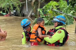 Các nhân viên cứu hộ đang sơ tán một đứa trẻ bị mắc kẹt do lũ lụt ở Sateng Nok, tỉnh Yala, Thái Lan. Ảnh: Reuters