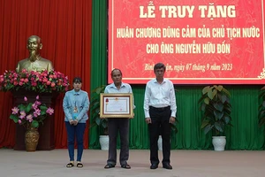 Thân nhân gia đình anh Nguyễn Hữu Đốn (vợ và cha bên trái hình) nhận Huân chương Dũng cảm của Chủ tịch nước truy tặng (Ảnh: CACC)