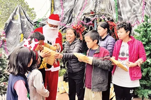 Một thành viên nhóm thiện nguyện đóng vai ông già Noel tặng quà Giáng sinh cho trẻ em ở mái ấm Thánh Tâm.