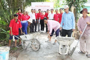 Thành viên Hội Chữ thập đỏ xã Đông Thạnh, thị xã Bình Minh (tỉnh Vĩnh Long) tham gia vá đường giao thông nông thôn. (Ảnh: BÁ DŨNG)