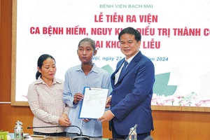 PGS, TS Đào Xuân Cơ, Giám đốc Bệnh viện Bạch Mai trao giấy ra viện cho bệnh nhân Nguyễn Quốc Trình. (Ảnh: THẾ ANH)