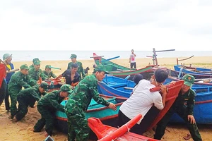 Bộ đội Biên phòng Quảng Bình giúp người dân chuyển thuyền đánh cá lên bờ chạy bão số 4.