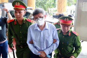 Lực lượng chức năng dẫn giải bị cáo Nguyễn Thanh Long (cựu Bộ trưởng Y tế) đến phiên tòa. (Ảnh: Phạm Kiên/TTXVN)
