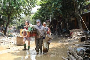 Người dân lội bùn khi di chuyển trên 2 tuyến phố Thanh Niên và Trần Hưng Đạo (thành phố Yên Bái, tỉnh Yên Bái), chiều 14/9. (Ảnh: Tuấn Anh/TTXVN)