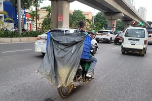 Một shipper không đội mũ bảo hiểm, treo bao tải che kín biển số, vừa lái xe vừa xem điện thoại trên đường Trần Phú (Hà Đông, Hà Nội). Ảnh | MẠNH TRƯỜNG