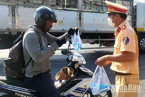 Chiến sĩ Phòng Cảnh sát giao thông Công an tỉnh Đồng Nai đội nắng, phát nước suối, khăn lạnh cho người dân đi xe máy về quê nghỉ lễ.