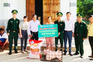 Đồng chí Tín (đứng ngoài cùng bên trái) và đồng đội tặng heo giống cho hộ nghèo khu vực biên giới biển.
