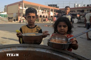 Trẻ em nhận thức ăn cứu trợ tại thành phố Khan Younis, Dải Gaza. (Ảnh: THX/TTXVN)