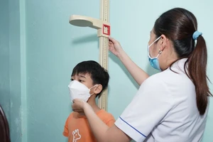 Nhân viên y tế đo chiều cao cho trẻ khi tham gia tầm soát.