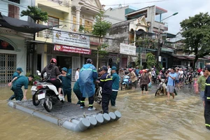 Lực lượng dân quân phường Minh Khai, thành phố Hà Giang đưa người dân qua đoạn đường ngập úng.