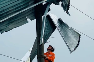 Công nhân Điện lực Bát Xát (Lào Cai) gỡ mái tôn khỏi cột điện.
